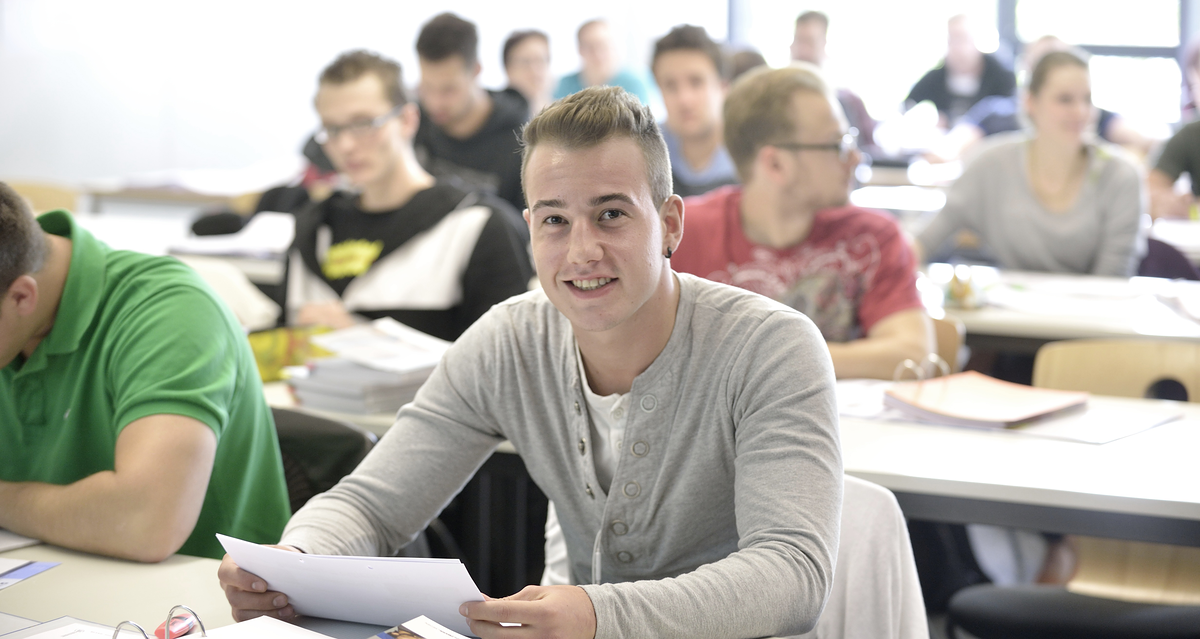 Tischreihen, hintereinander, erste Reihe, Teilnehmer Blick vorne, lächelt, Hintergrund unscharf, Bachelorstudiengang_Unternehmensführung_15585_argum