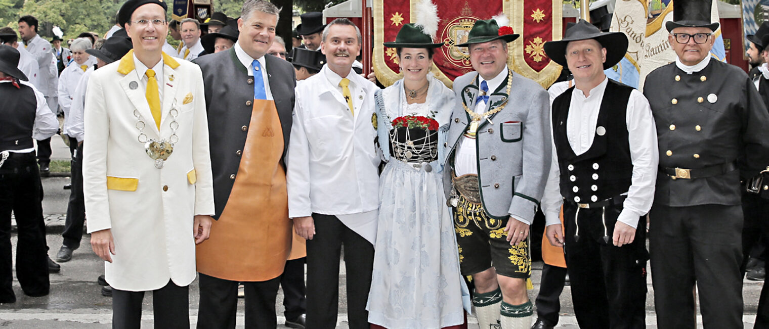Claudius Wolfrum (Vorstand Maler und Lackierer Innung), Thomas Bauer (Obermeister Metall-Innung), Johann Raab (Vorstand Metzger-Innung), Natalie und Josef Schmid (Zweiter Bürgermeister der Stadt München), Albert Aumann (Obermeister Zimmerer-Innung) und Wolfgang Batz (Obermeister Kaminkehrer-Innung; v.li.n.re.) vor Beginn des Trachten- und Schützenzugs.