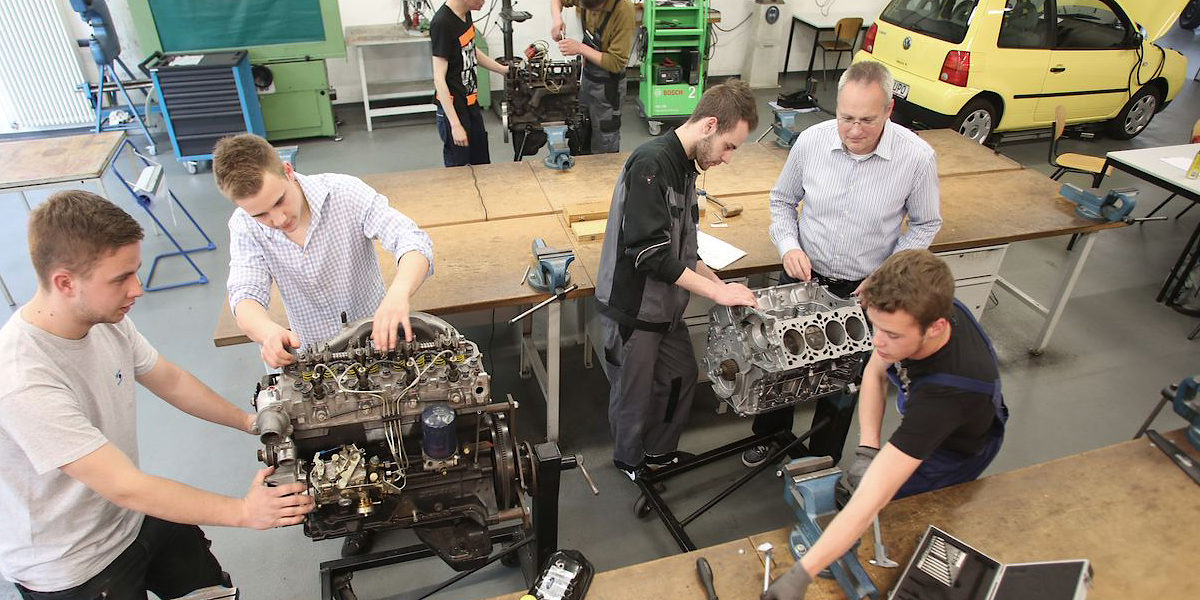 Lehrwerkstatt, ÜLU, Kfz, Unterricht, Ausbildung, Lehrlinge, Männer, Ausbildungsmeister, Gruppenfoto, Auto, Hebebühne, Messgeräte, Werkbank