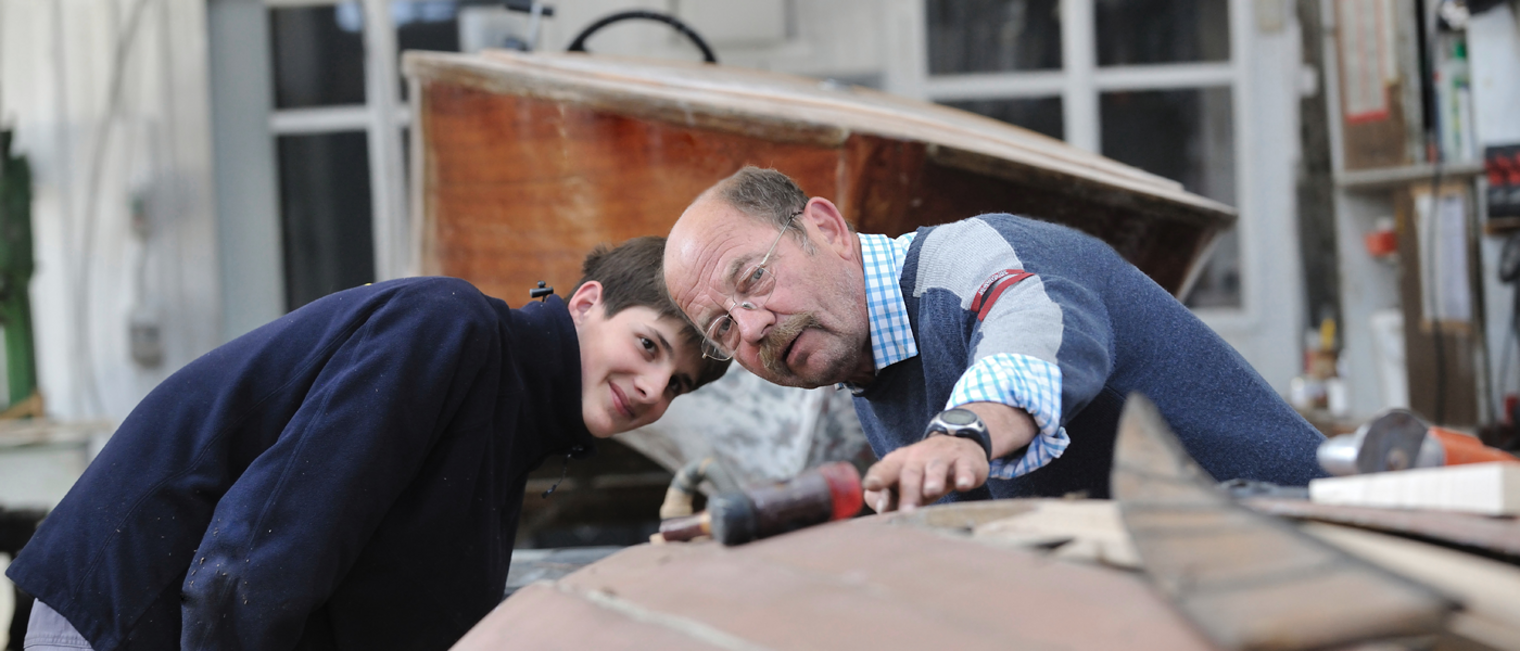 Meister, Lehrling, Praktikant, Bootsbauer, Schiffbauer, Boot, Schiff, Holz, Werkzeug, Unterweisung, Innenaufnahme, Werkstatt, Erklärung Handwerk, Trade, Werft, Shipyard, Rambeck, Arbeiter, Worker, Boot, Boat, Bootsbauer, Segelboot, Scherenkreuzer, Yachthafen, Bootsvertrieb, Starnberger See, See, Lake, Binnensee, Kultur, Culture, Tradition, Schiffsbauer, Maritim, Segeln, Sailing, 17108