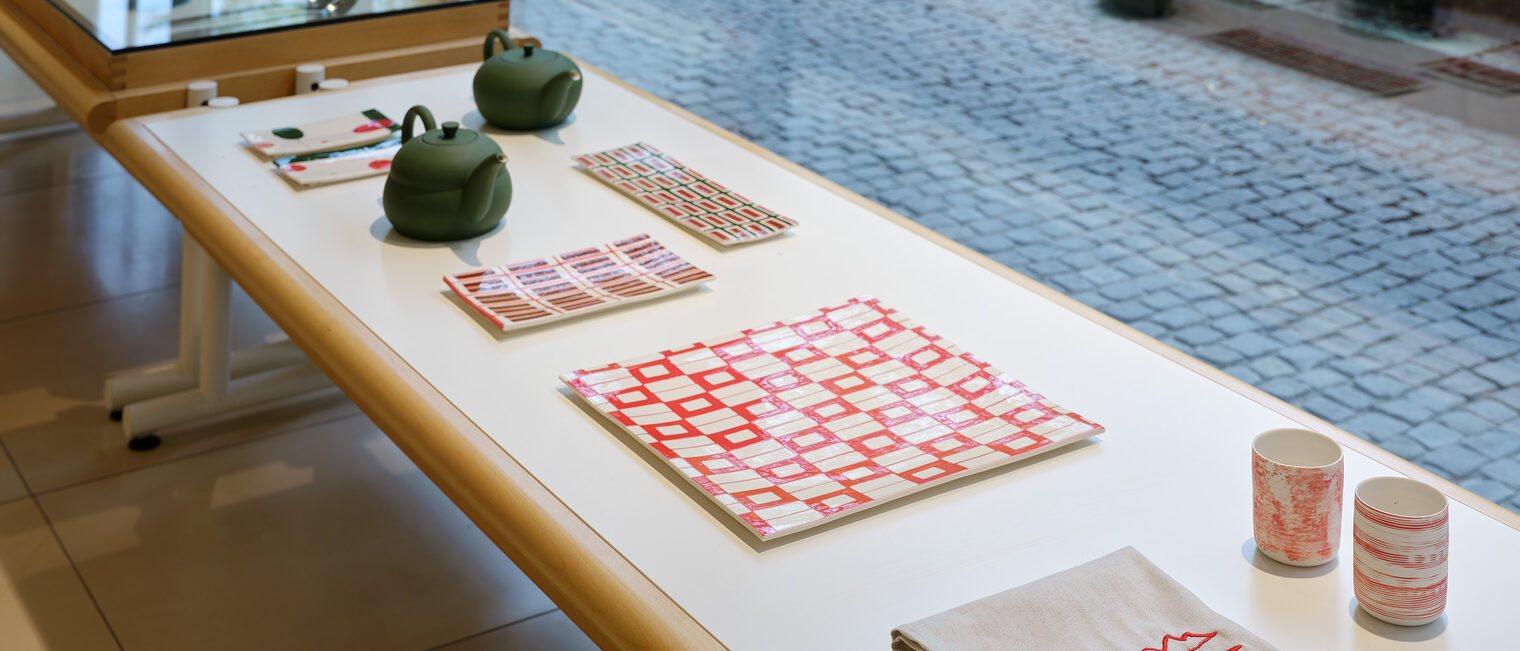 Teatime Gedeck, Teekannen, Becher, Stoffservietten auf einem Tisch mit Blick aus der Galerie Handwerk, Kunstblock München.