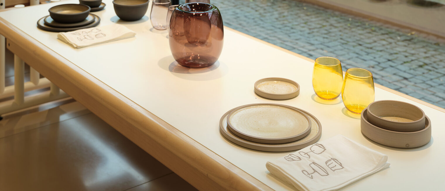 Gedeck Blick aus der Galerie mit Kunstobjekten aus der Ausstellung Tischkultur mit Gläsern, Karaffe, Schüsseln, Tassen, Tellern