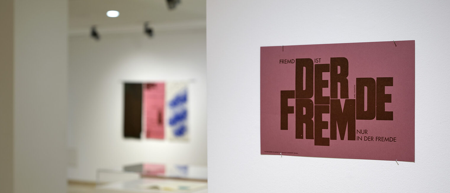 Bild in himbeerfarben mit der Aufschrift Fremd ist der Fremde nur in der Fremde. Karl Valentin