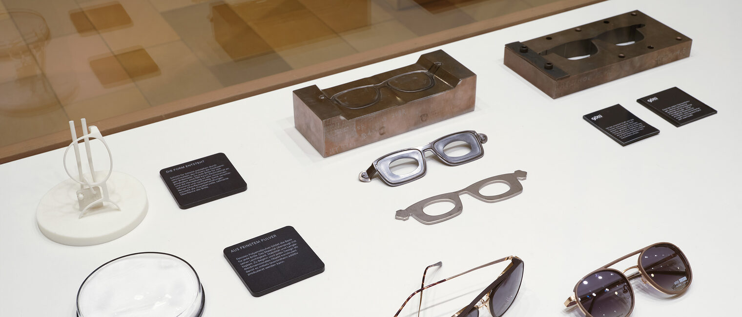 Sonnenbrille und Modelle für Brillen im Schaukasten der Reise-Ausstellung der Galerie Handwerk in der Maxvorstadt.