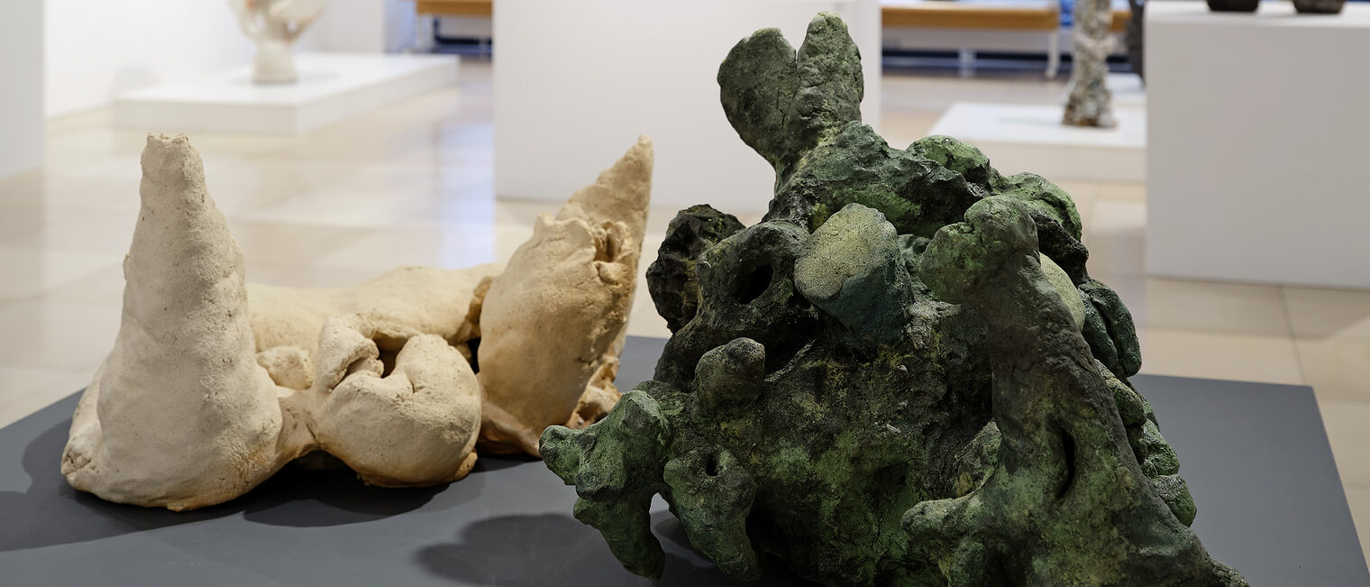 Im Vordergrund eine moosgruene, daneben eine sandfarbene Skulptur, die an Korallenriffe erinnern.