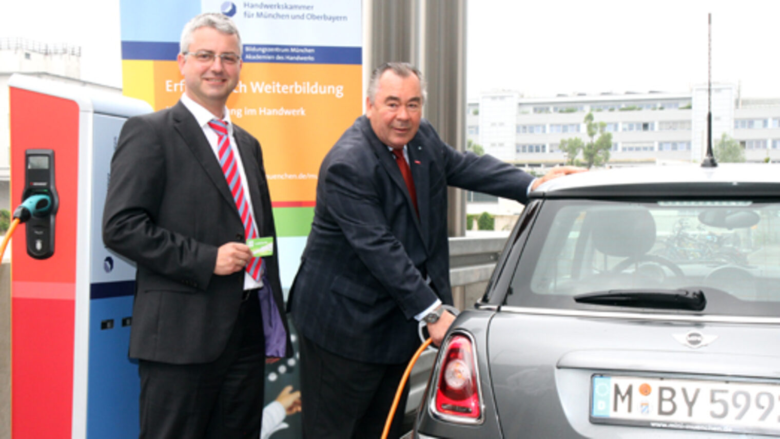 Handwerkskammerpräsident Heinrich Traublinger, MdL a. D.(rechts) und Dr. Wilfried Ruß von den Stadtwerken München nahmen die Stromtankstelle beim Bildungszentrum München der Handwerkskammer in Betrieb.